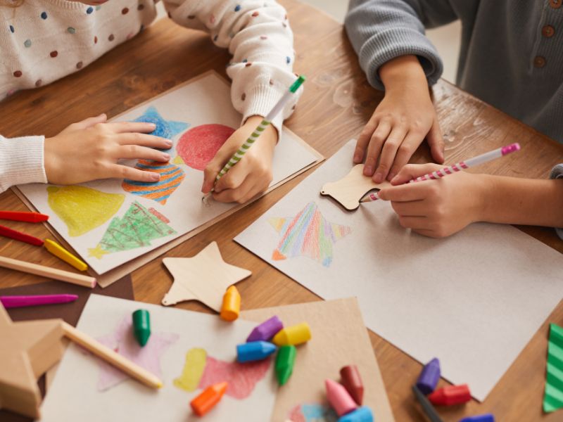 crianças utilizando materiais de pintura enquanto desenham